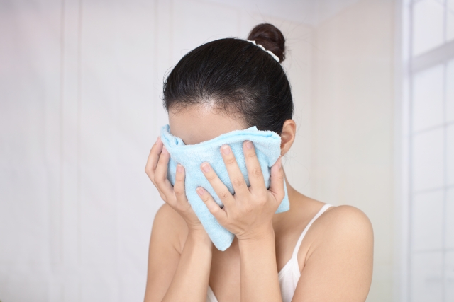 毛穴を広げるために蒸しタオルを顔に乗せる女性